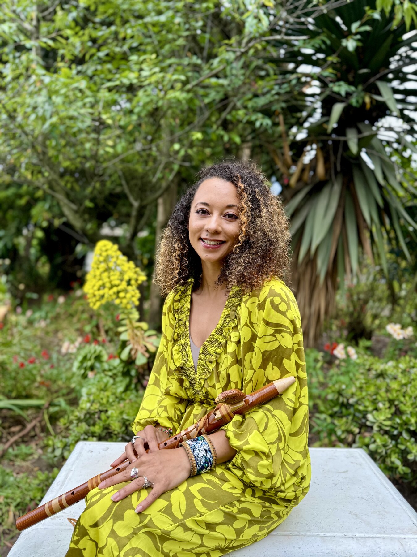 Zai’Ra Paige holding a wooden flute in a garden