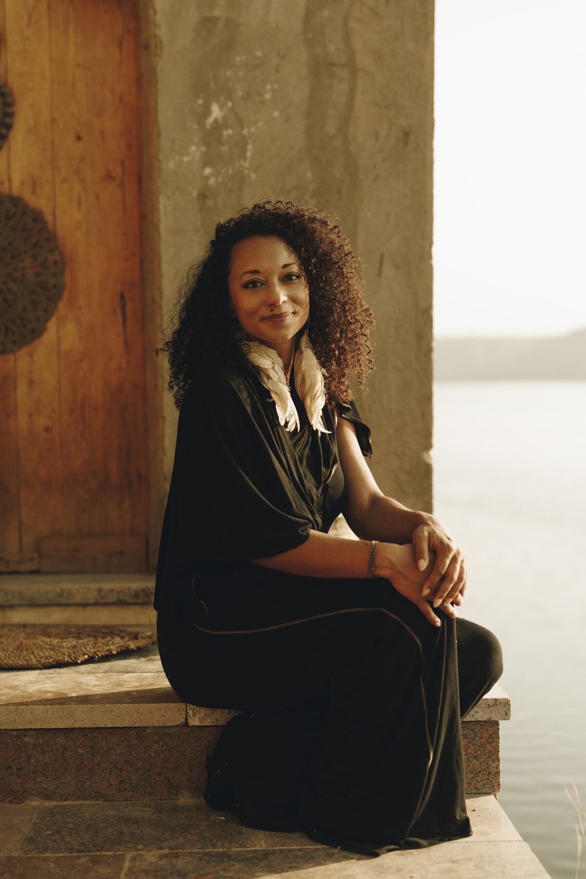 Zai’Ra Paige seated beside a stone doorway overlooking the water